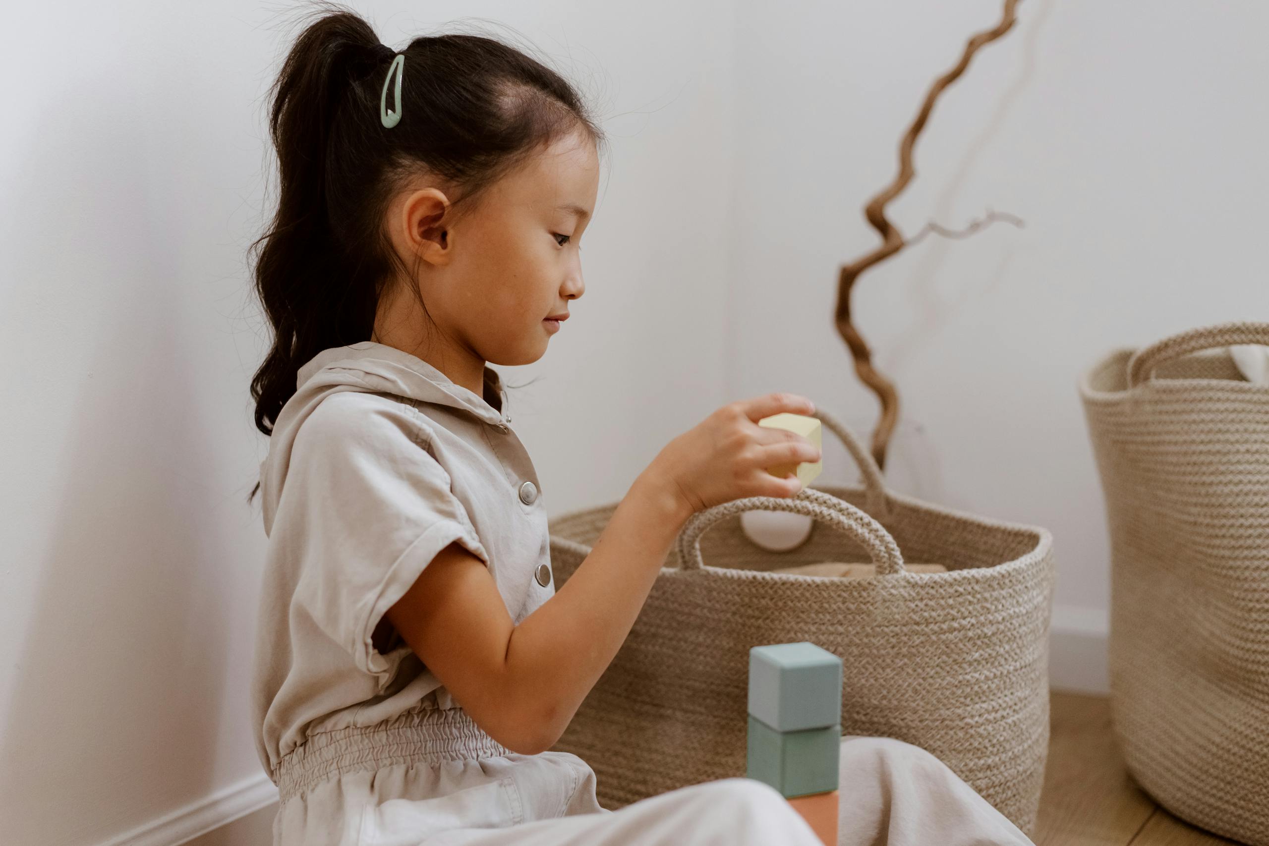 A young girl organizing toys in a basket, creating a tidy and peaceful home environment.